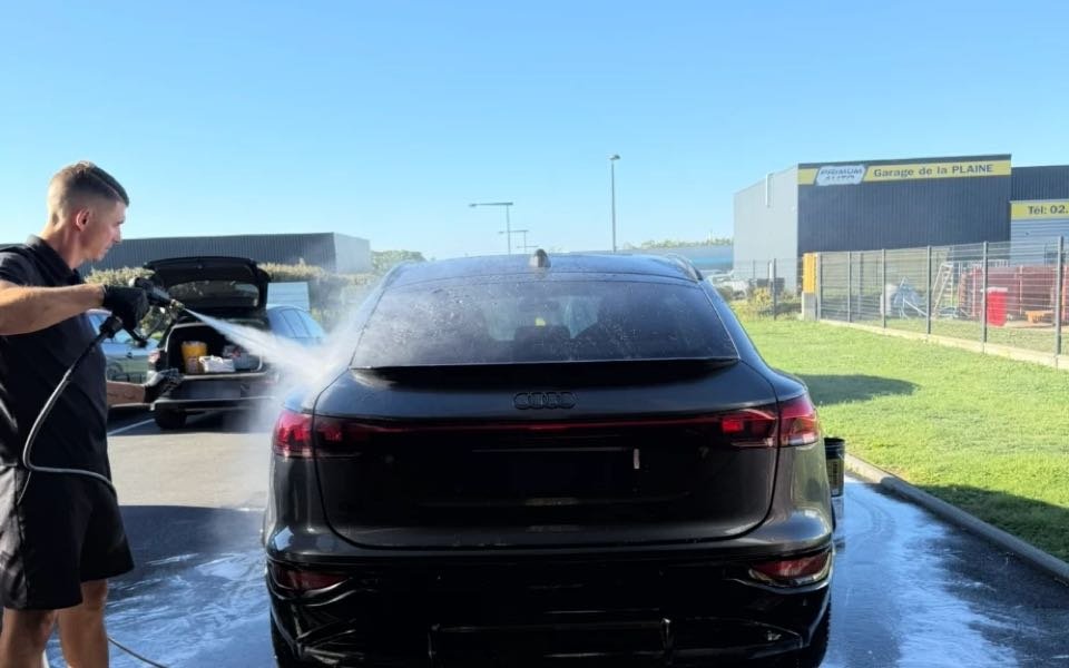 Lavage d'une voiture noire au nettoyeur haute pression